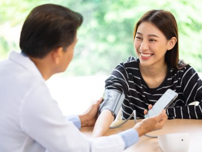 Senior doctor using sphygmomanometer with stethoscope checking blood pressure to a patient in the hospital.